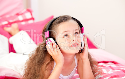 Adorable little girl listening music lying on her bed
