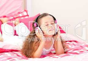 Beautiful little girl listening music lying on her bed