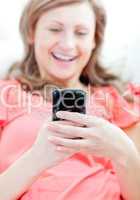 Laughing woman sending a text lying on a sofa