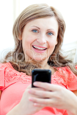 Radiant woman sending a text lying on a sofa