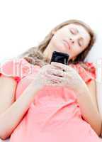 Tired woman sending a text lying on a sofa