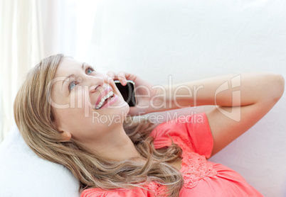 Jolly woman talking on phone lying on a sofa