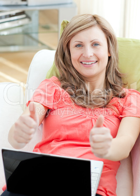 Successful woman using a laptop sitting on a sofa