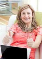 Successful woman using a laptop sitting on a sofa