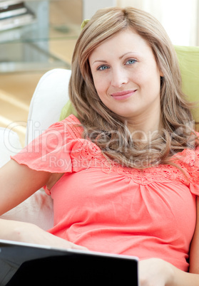 Smiling woman using a laptop sitting on a sofa