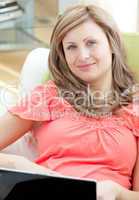 Smiling woman using a laptop sitting on a sofa