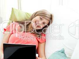 Jolly woman using a laptop sitting on a sofa