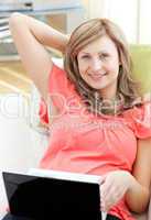 Beautiful woman using a laptop sitting on a sofa