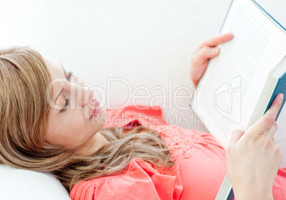 Relaxed woman reading a book lying on a sofa
