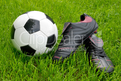 Fußballschuhe und Ball auf Rasen