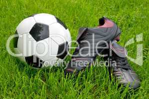 Fußballschuhe und Ball auf Rasen