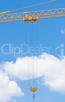 Crane hook over blue sky with clouds