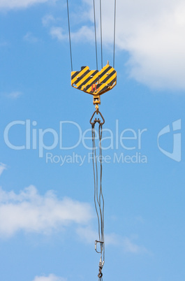 Crane hook over blue sky with clouds