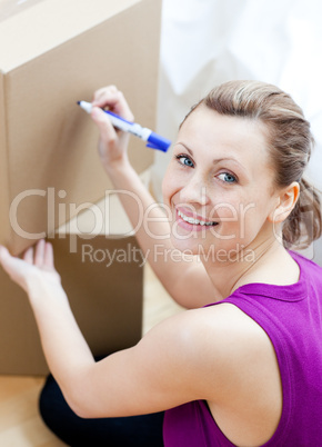 Happy woman writing on a box
