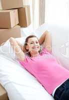 Delighted woman relaxing on a sofa with boxes