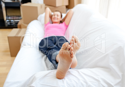 Confident woman relaxing on a sofa with boxes