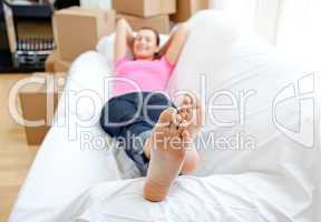 Confident woman relaxing on a sofa with boxes