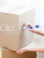 Cute woman writing on a box at home
