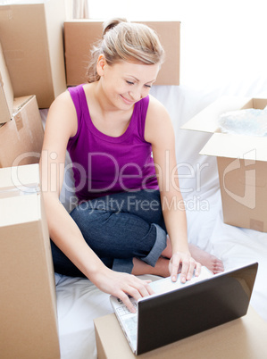 Beautiful woman using a laptop while unpacking box