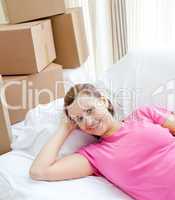 Happy woman relaxing on a sofa with boxes