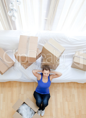Tired woman sitting between boxes