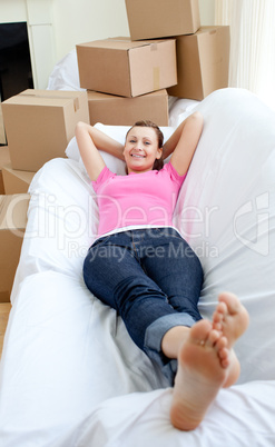 Cute woman relaxing on a sofa with boxes