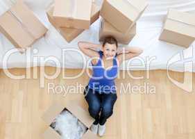 Beautiful woman sitting between boxes at home