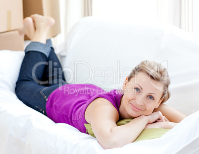 Portrait of a joyful woman relaxing on a sofa with boxes