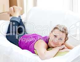 Portrait of a joyful woman relaxing on a sofa with boxes