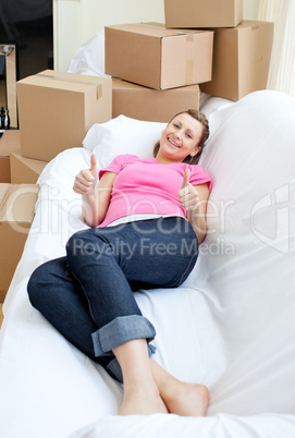 Bright woman relaxing on a sofa with boxes