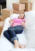 Bright woman relaxing on a sofa with boxes