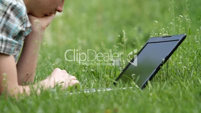 teenager with laptop on grass.