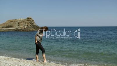 Woman sits on a rocky beach