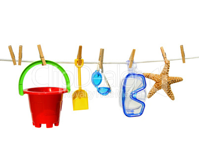 Child's summer toys on clothesline against white