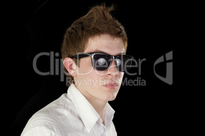 Young man with sunglasses posing on a black background