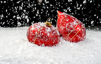 Snow falling on two red ornaments