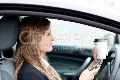 Blond businesswoman sending a text while driving