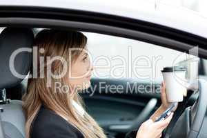 Blond businesswoman sending a text while driving