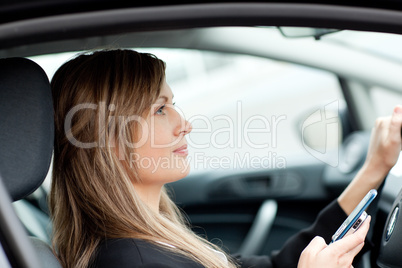 Attractive businesswoman sending a text while driving to work