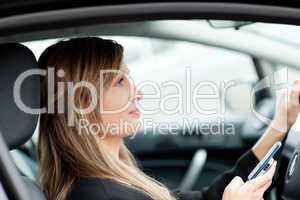 Attractive businesswoman sending a text while driving to work
