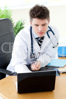 Confident male doctor using a laptop