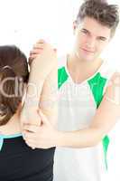 Smiling physical therapist checking a woman's shoulder