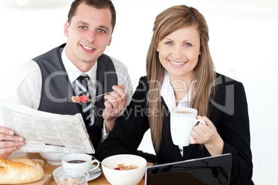 Young couple of business people reading a newspaper while having