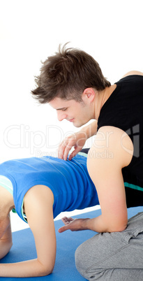Caucasian woman working out assited by her personal trainer