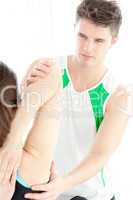 Confident physical therapist checking a woman's shoulder