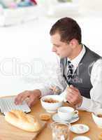 Young businessman using a laptop while having breakfast