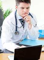Worried male doctor using a laptop