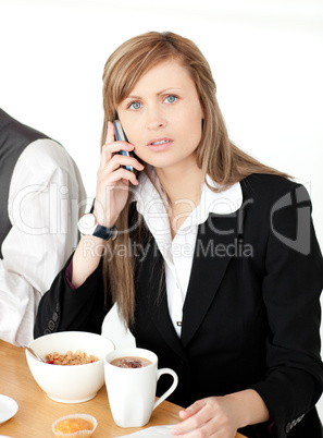 Worried businesswoman talking on phone while having breakfast