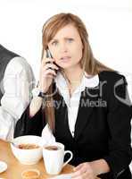 Worried businesswoman talking on phone while having breakfast