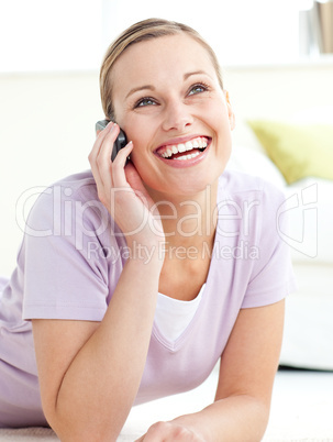 Delighted woman talking on phone lying on the floor